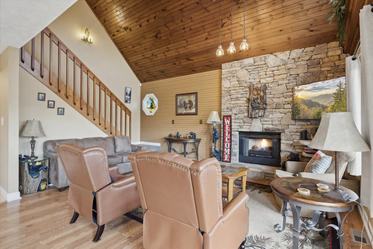 A warm interior living space featuring a stone fireplace, exposed wooden beams, and comfortable seating. The inviting décor and soft lighting create a cozy ambiance for evenings by the fire.