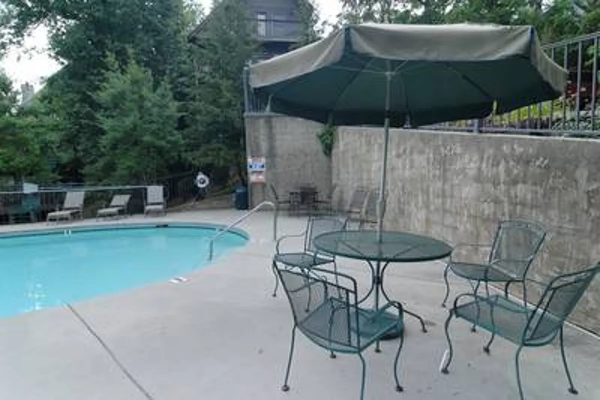 A sparkling swimming pool surrounded by comfortable outdoor seating and an umbrella, inviting guests to swim, sunbathe, or gather for fun poolside activities in a friendly community setting.