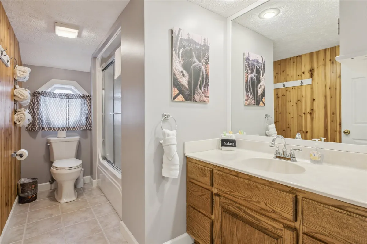 A stylish, modern bathroom with a double mirrored sink area, wood paneling, and decorative artwork. The clean lines and elegant fixtures evoke a spa-like atmosphere, making it an inviting place for unwinding and personal care.